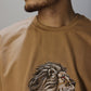 Man wearing a brown t-shirt with an embroidered design of a face with hair.